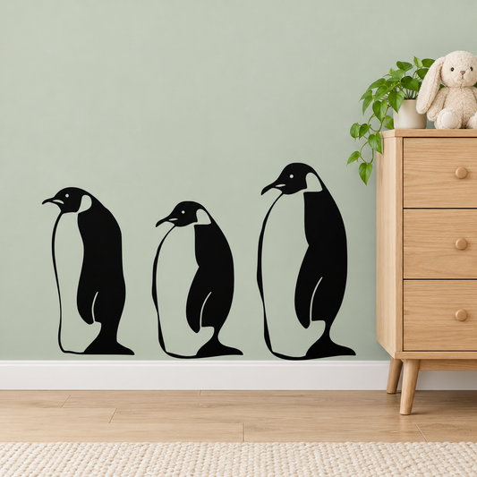 Three black penguin wall decals on a sage nursery wall beside an oak dresser