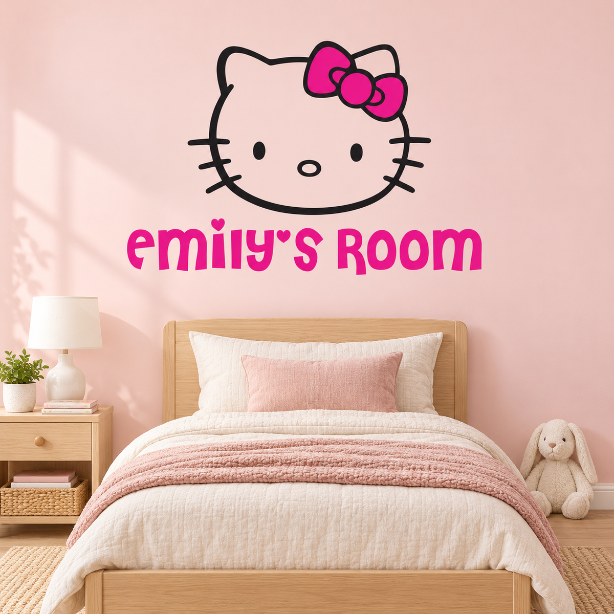 Personalized bow cat wall decal with pink name lettering above an oak bed in a blush bedroom